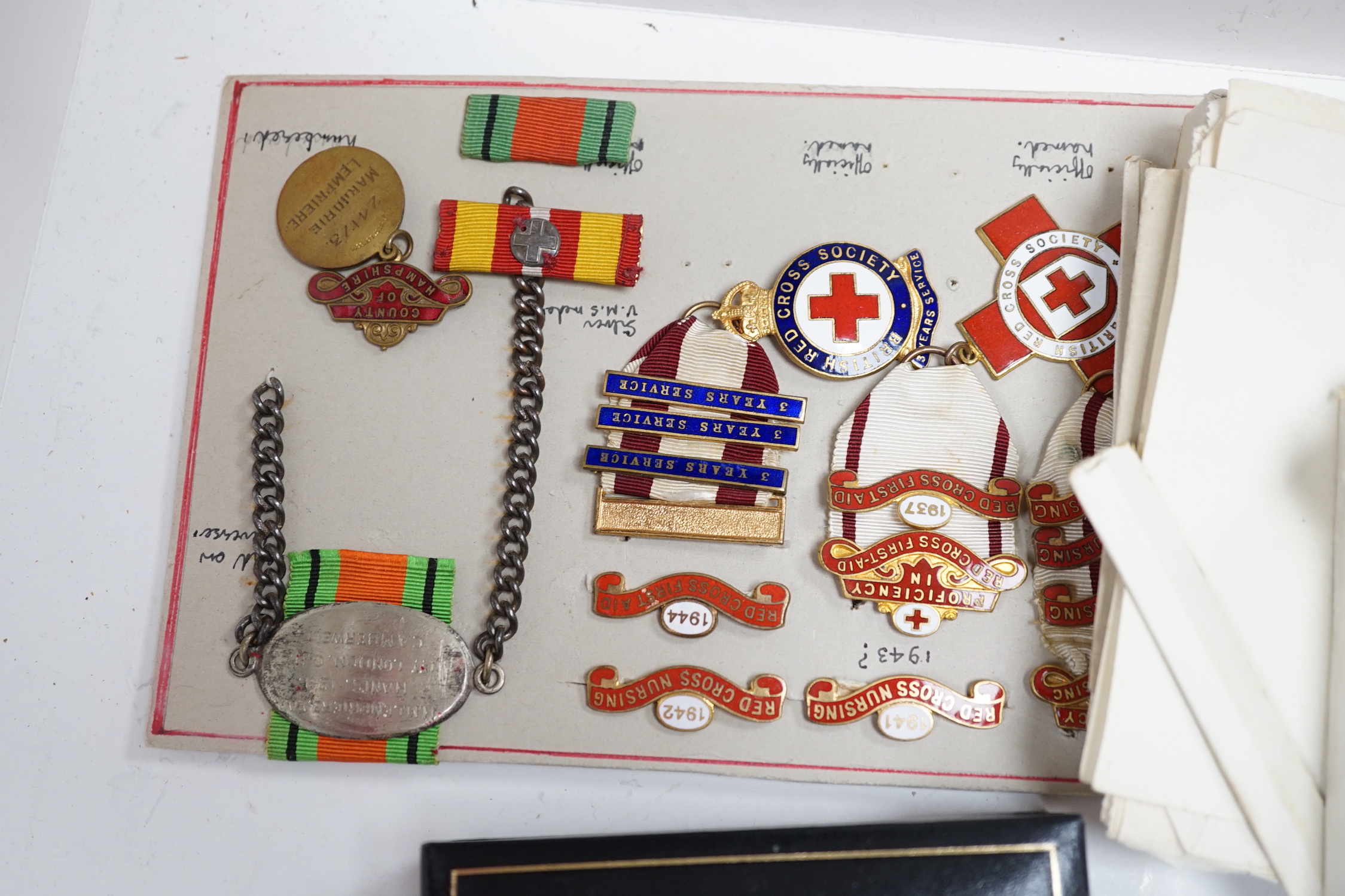 A collection of British Red Cross, medals, badges and memorabilia including a brass plaque, commemorating an auxiliary hospital during the Great War, proficiency, medals, long, service, medals, metal boxes, and some pape
